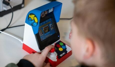 a boy playing a game on a mini arcade gaming machine