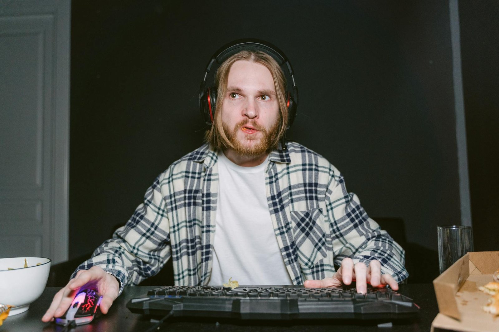 man in plaid long sleeve shirt playing online gaming with a computer