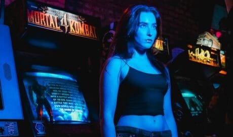 a retro gamer woman standing in front of a row of arcade games