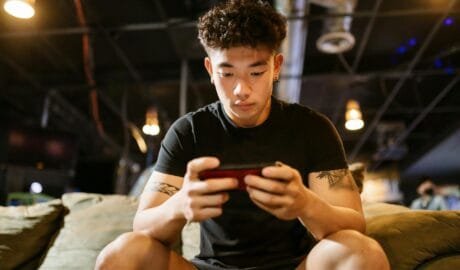 man in black crew neck t shirt playing mobile game