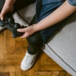 a person sitting on gray couch holding a game controller