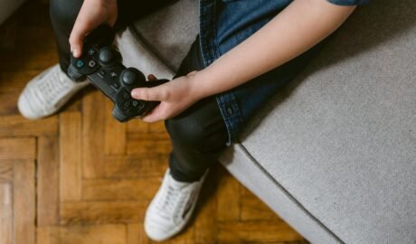 a person sitting on gray couch holding a game controller